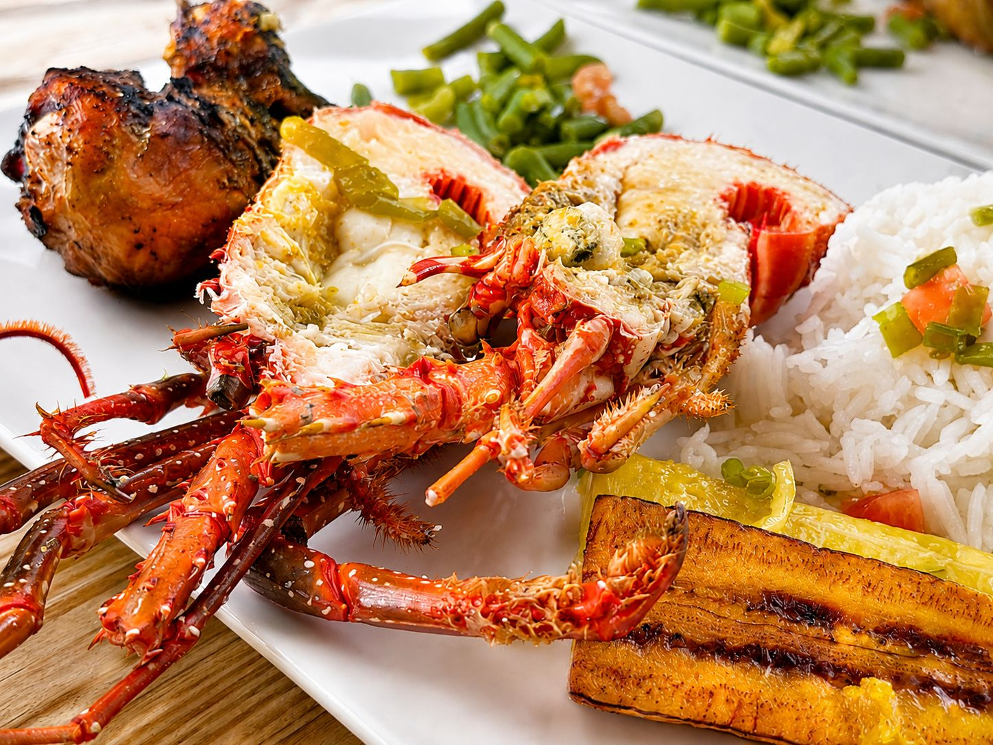 Gros plan sur une assiette de langouste grillée, poulet boucané et riz créole