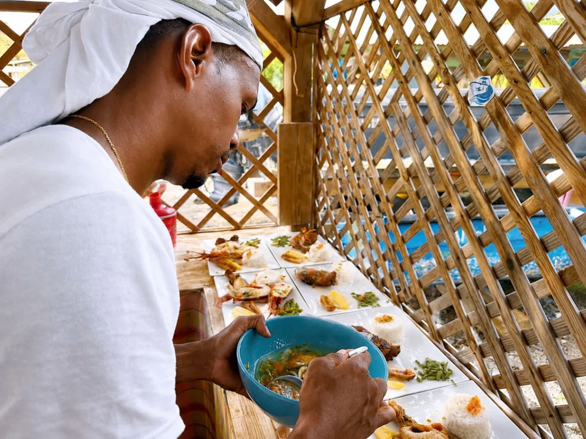 Kenny qui prépare les assiettes de langouste et de riz avant le repas