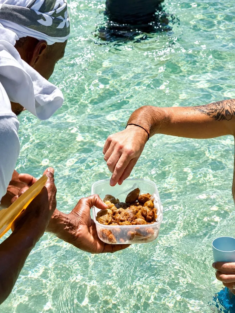 Main qui attrape des accras dans l'eau turquoise pendant la sortie en mer
